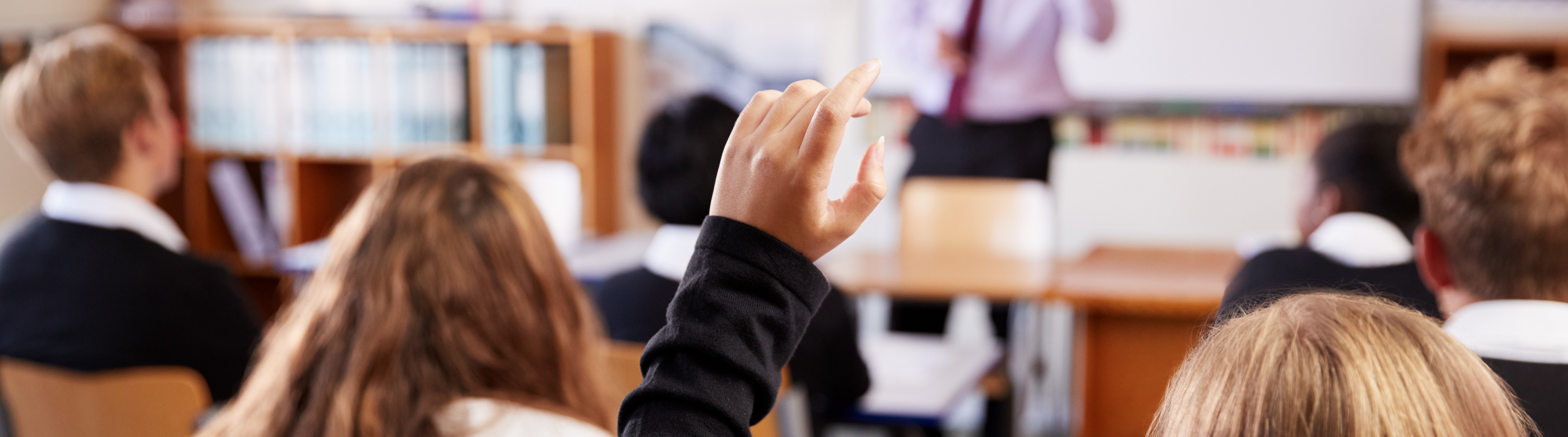 Learners with their hands up in a classroom