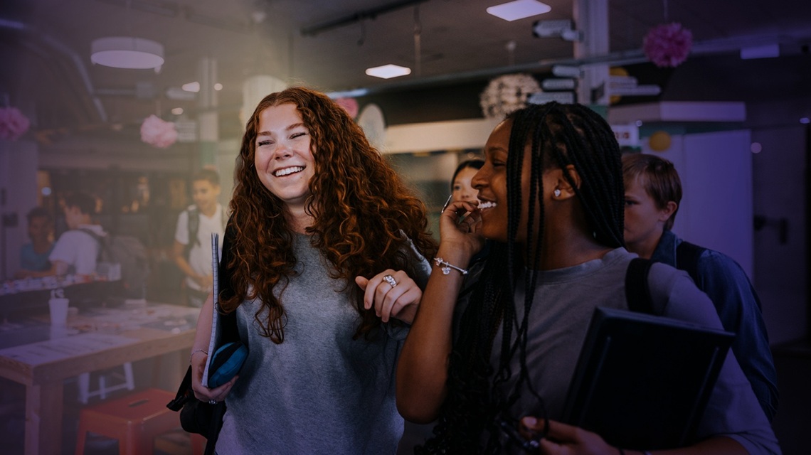 Students laughing whilst walking through a classroom